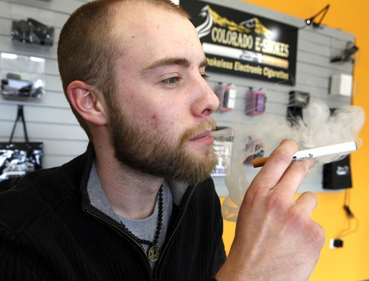 Blair Roberts, 22, a sales associate at Colorado E-Smokes in Aurora, Colo., demonstrates the use of an electronic cigarette and the vapor it emits.