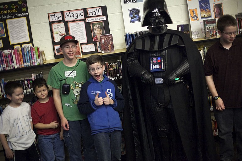 Boys pose for photos with Darth Vader, in real life David Sherman, a member of Cloud City Garrison, a Star Wars club that raises money for charities.