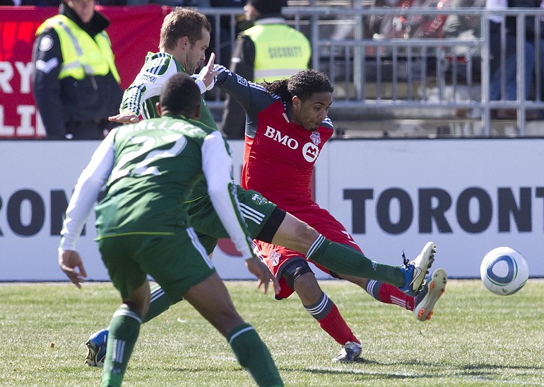 Toronto FC's Javier Martina, right, plays a ball into the penalty box despite pressure from Portland Timbers' Kevin Goldthwaite, center, and Rodney Wallace during second half MLS soccer action in Toronto on Saturday, March  26, 2011.