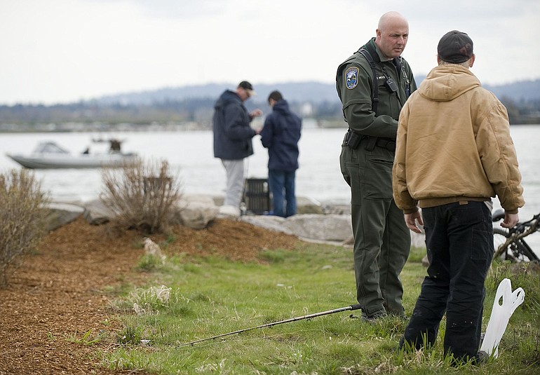 Washington Department of Fish and Wildlife Officer Tom Moats talks with fishermen along the Tidewater Cove jetty Sunday.