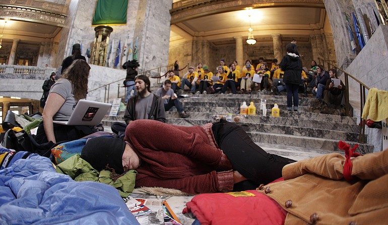 A protester who spent the night in the Capitol in Olympia sleeps on the floor of the rotunda, Thursday.