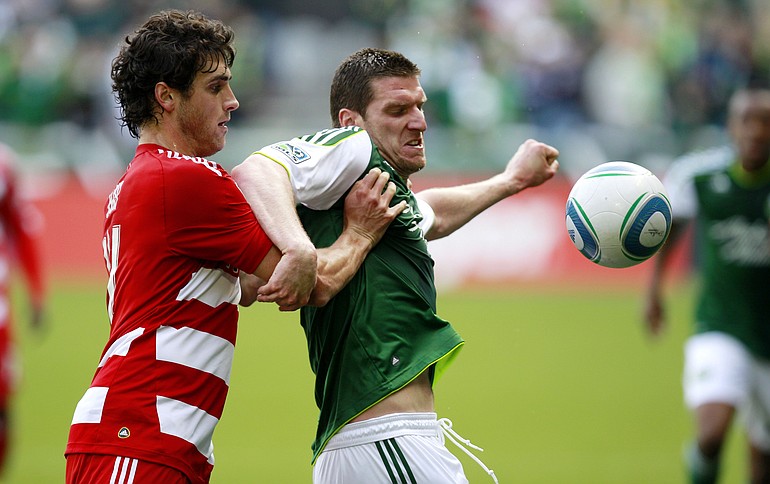 FC Dallas defender George John, left, and Portland Timbers forward Kenny Cooper, right, battle for the ball in the second half Sunday at Jeld-Wen Field.