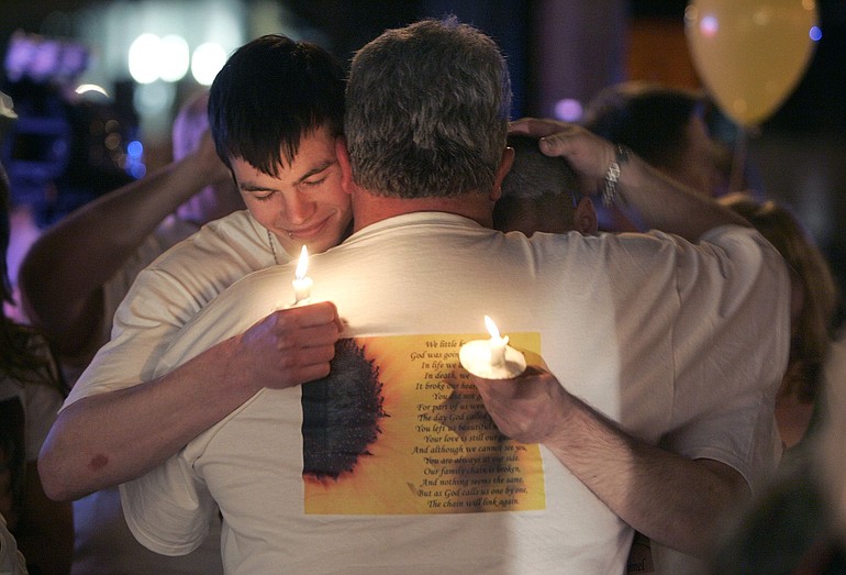 Erik Gittings, on left, and Dan Marciano hug Danielle Sale's father David Sale at the first anniversary memorial of Danielle's death.