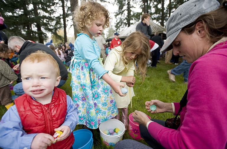 The McCusker family, from left, River, 1, Saige, 4, Cyenna, 5, and mom Melissa, crack open plastic eggs collected Sunday at the Crown Park hunt in Camas.