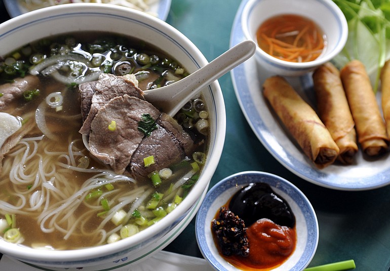 Beef Noodle Soup with top round steak and lean brisket, left, and egg rolls at Pho DaLat III in Vancouver.