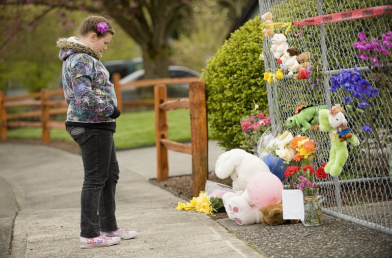 Angelina Belous, 8, reflects on a memorial Wednesday outside the home where six people died in an Easter morning fire.