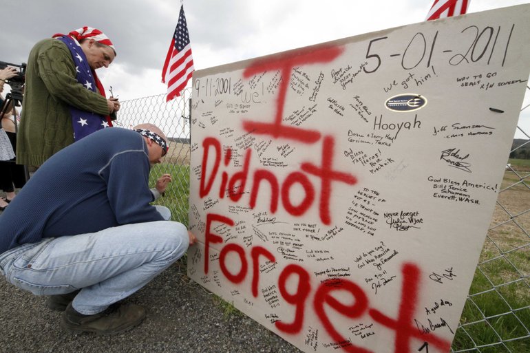 Jan Ray, left, and Jeff Ray attach a sign to the fence overlooking the crash site of United Flight 93 in Shanksville, Pa., on Monday after learning that Osama bin Laden had been killed.