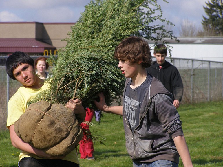 Tristan Bridges, left, and Tyler Boohml plant trees on the Frontier Middle School campus on Earth Day.