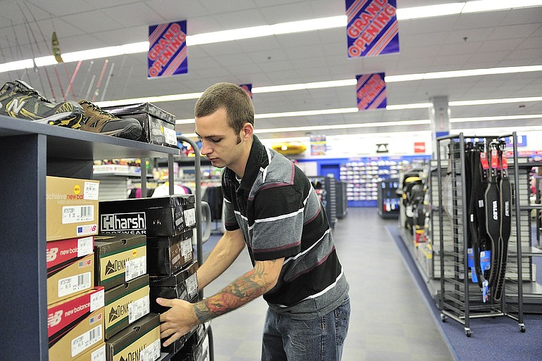 Mike Moody, a sales associate for Big 5 Sporting Goods, prepares a floor display of shoes in 2010 in Vancouver.
