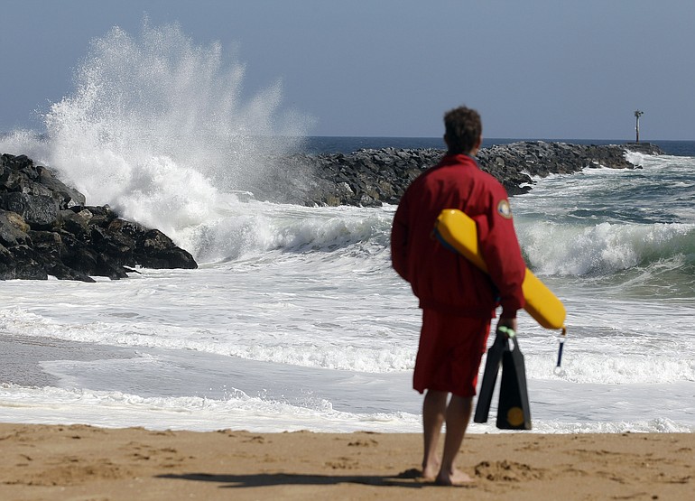 A Newport Beach life guard watches the high surf at the &quot;Wedge&quot; in Newport Beach, Calif.