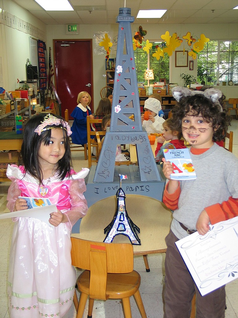 Chloe Liou and Jonas Drummond stand by a replica of the Eiffel Tower during French Week at Skinner Elementary Montessori School.