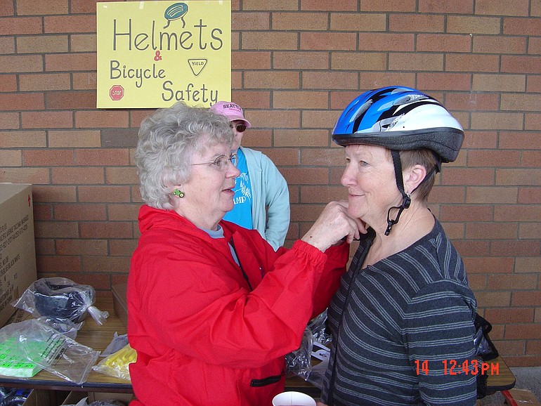 Marion Swenson adjusts a helmet for Lanell Wells at the Fircrest Neighborhood bike rodeo.