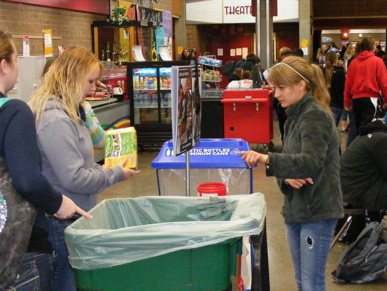 Alyssa Crosby, right, a Prairie High School junior, shows students where to discard scraps and waste in the Save Organic Scraps program.