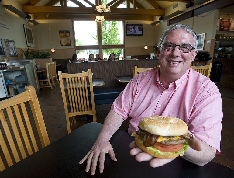 Burgerville President and CEO Jeff Harvey shows off one of the company's signature menu items, the Half-Pound Colossal cheeseburger with bacon at the company's Salmon Creek restaurant.