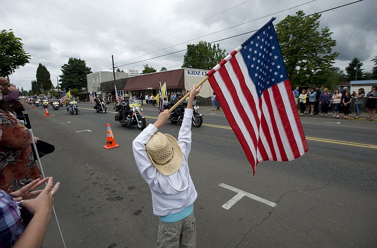 Taelynn Webster, 9, waves a flag this morning as the city of Battle Ground lines Main Street to honor police Officer Michael Molzahn who drowned in the Columbia River while off duty on Sunday.
