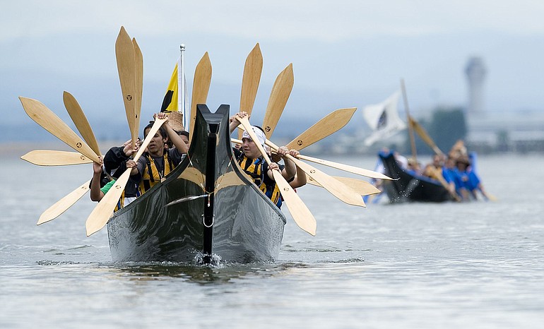 Members of the Confederated Tribes of Warm Springs fan their paddles in a salute to a group of people on shore Thursday.