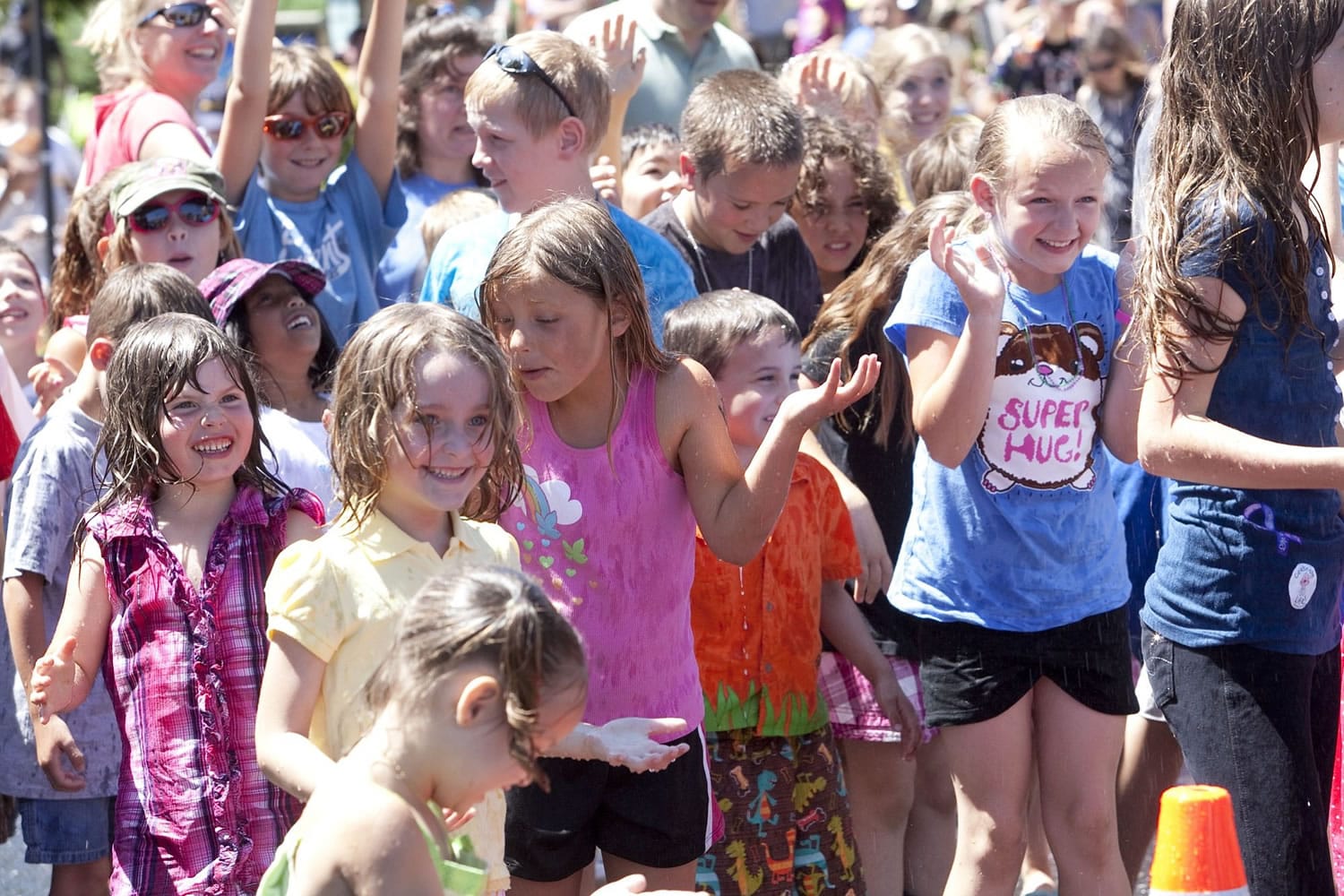 Children cool down in the spray of a fire hose between bathtub races at the Camas Days festival.