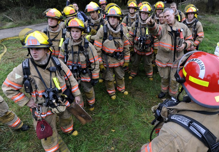 Capt. Jeff Gaines, right, points out a home's key features to a group of firefighter recruits before the live fire exercise. Recruits will graduate from training on Nov.
