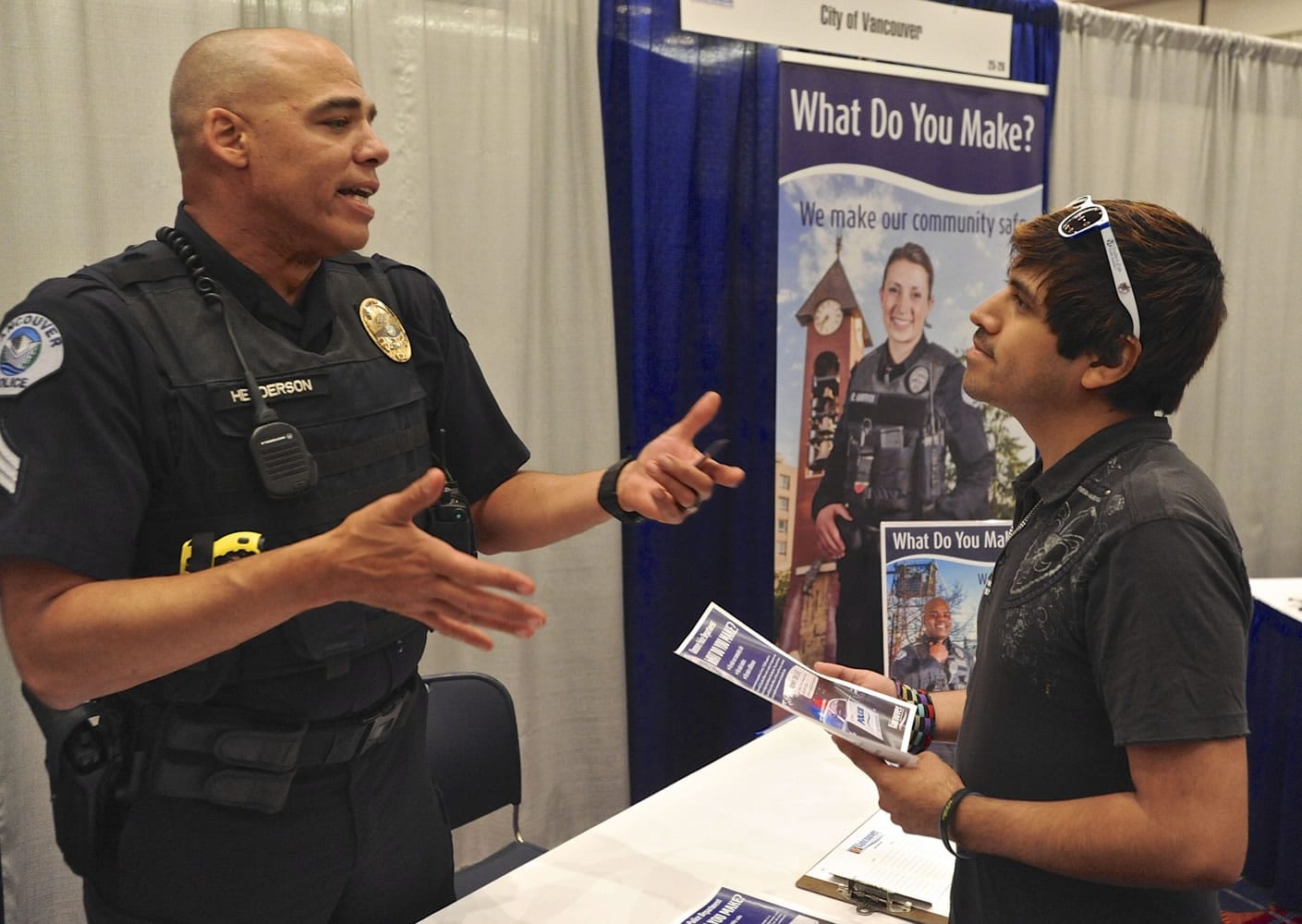 Sgt. Dave Henderson speaks with Frankie Cordova about job opportunities at Vancouver Police Department at a recent Hispanic Job Fair in Portland.