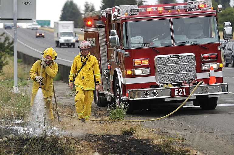Volunteer firefighter Tyler Edwards, left, and Captain Ryan Berg, right, of Clark County Fire and Rescue extinguish one of a series of grass fires that broke out before 10 a.m. Friday along northbound Interstate 5.