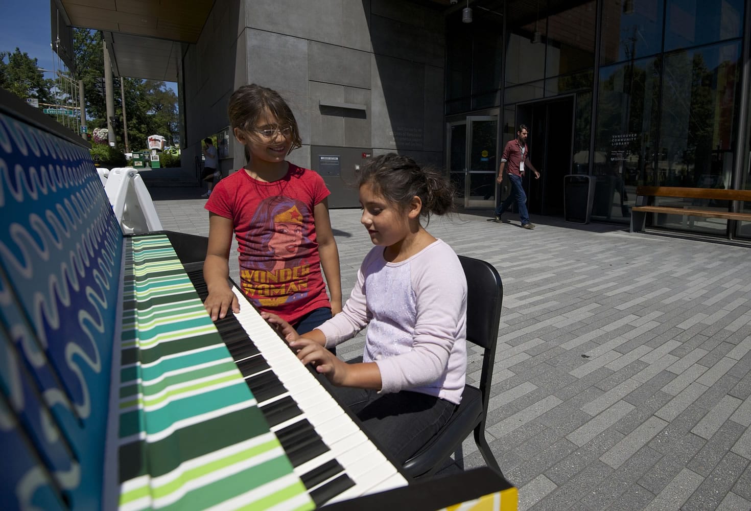 Edna Flores, center, and Christina Arales examine a piano in front of the Vancouver Community Library on Friday.