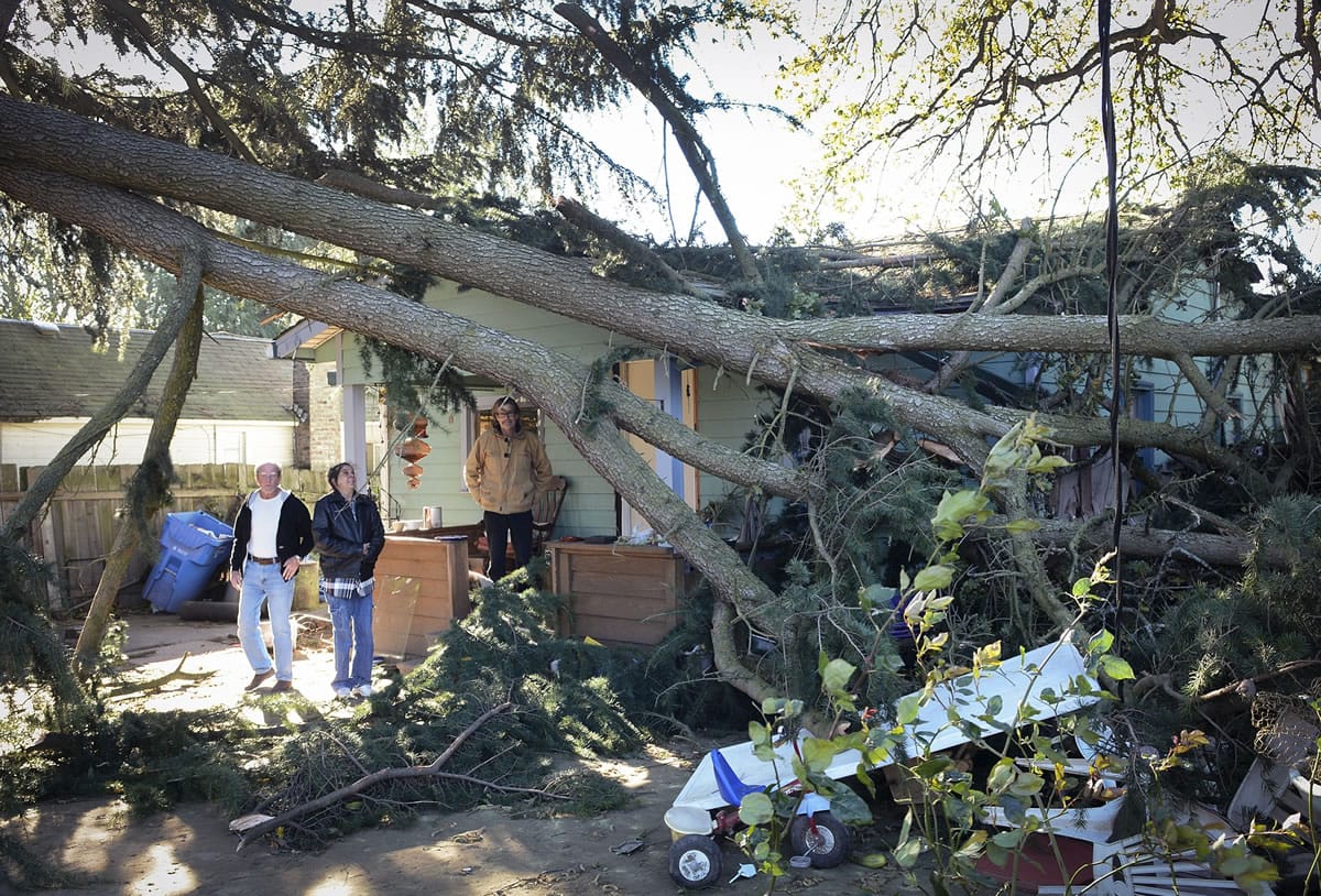 Roommates Roy Sorrick, Annie Cramer and Jim Childress observe the damage to their home from large tree limbs that fell Tuesday during a wind storm.
