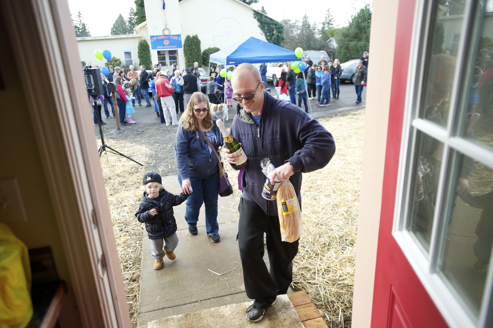 Charles Frost, right, leads his family, from left, Charles Deacon, 2, Michelle and 8-year-old Serenity (behind her dad) into their new home. Well-wishers had just given them the traditional housewarming gifts of bread, salt and wine.