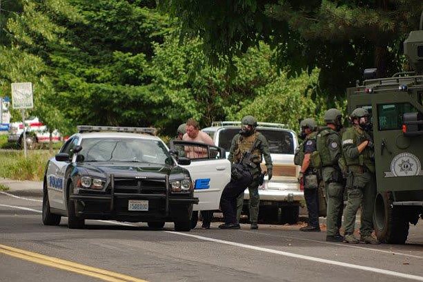 Officers from the Southwest Washington Regional SWAT Team take a man into custody after a four-hour standoff Saturday on East 18th Street in Vancouver. The man, whose name was not released Saturday, was wanted for violation of a restraining order and had a warrant related to a domestic violence incident.