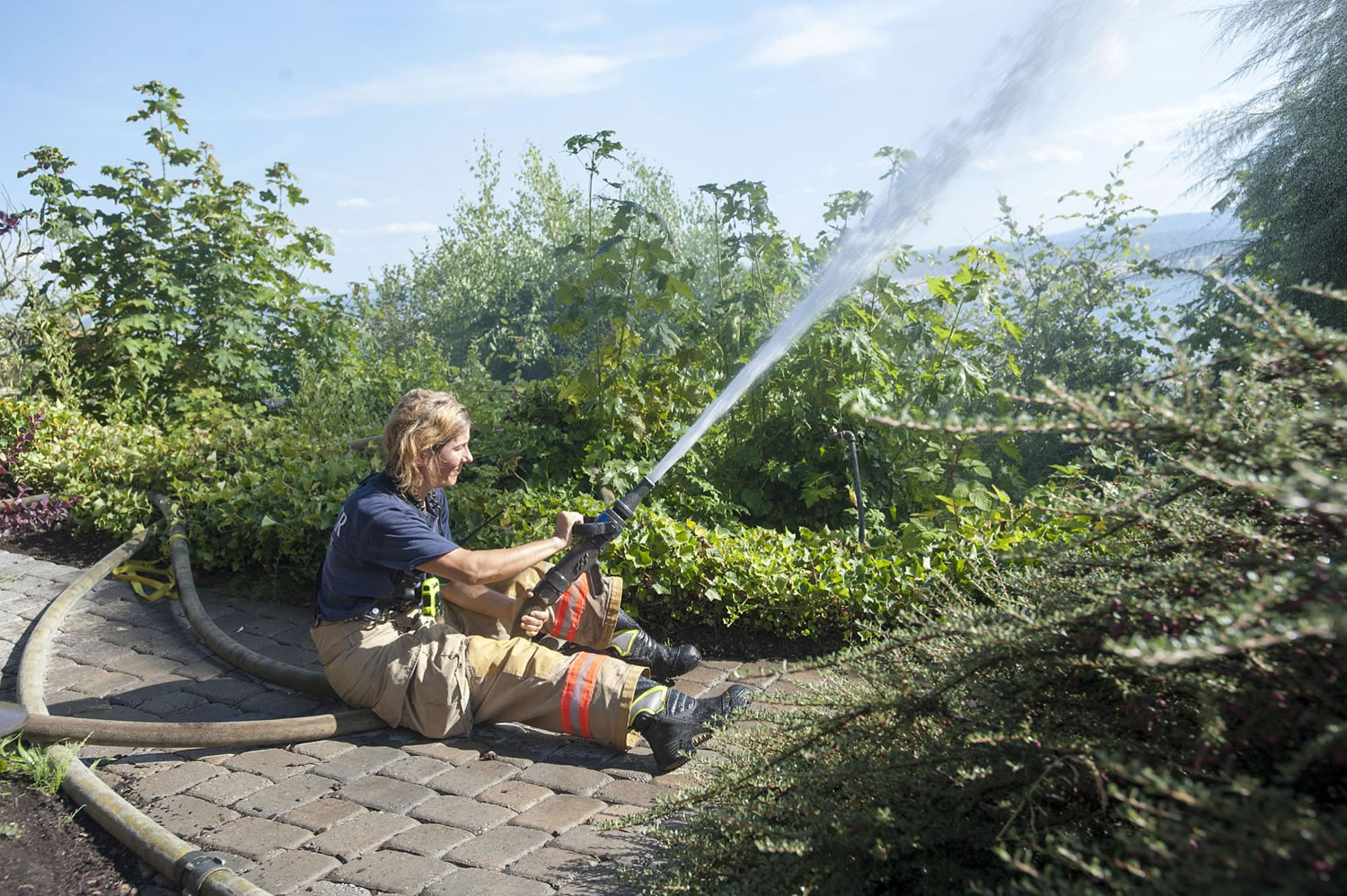 Fire fighter Heidi Parr in action during a fire on Buena Viata Drive in Vancouver on Wednesday. Firefighters fought multiple house fires on Wednesday. The first started at about 4:45 p.m. as a brush fire and spread to a house in the 5700 block of Buena Vista Drive.