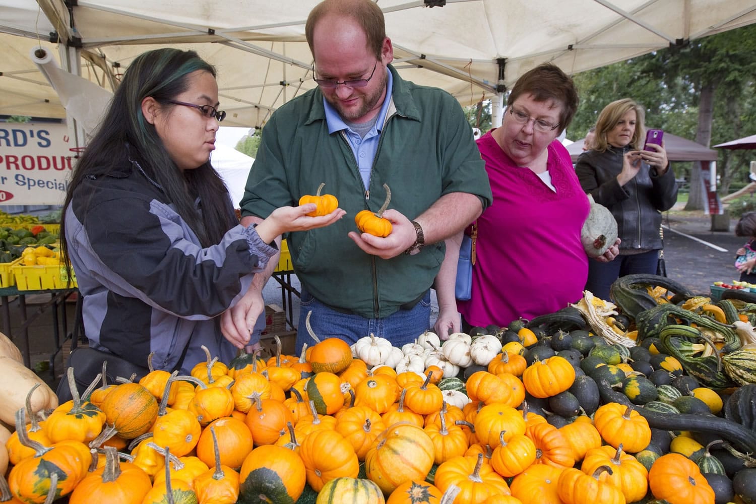From left, Bonnie James, Matt James and Linda James select small pumpkins on sale Sunday, the last day of the Vancouver Farmers Market's 25th season.