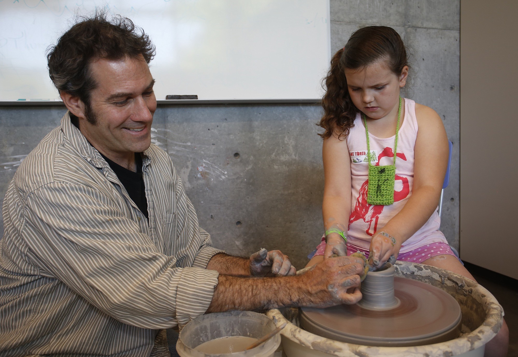 Pottery instructor Chuck Masi helps 7-year-old Kaylee Gibbs of Vancouver form a clay pot on the wheel during the Marshall Community Center's family fun day Saturday.