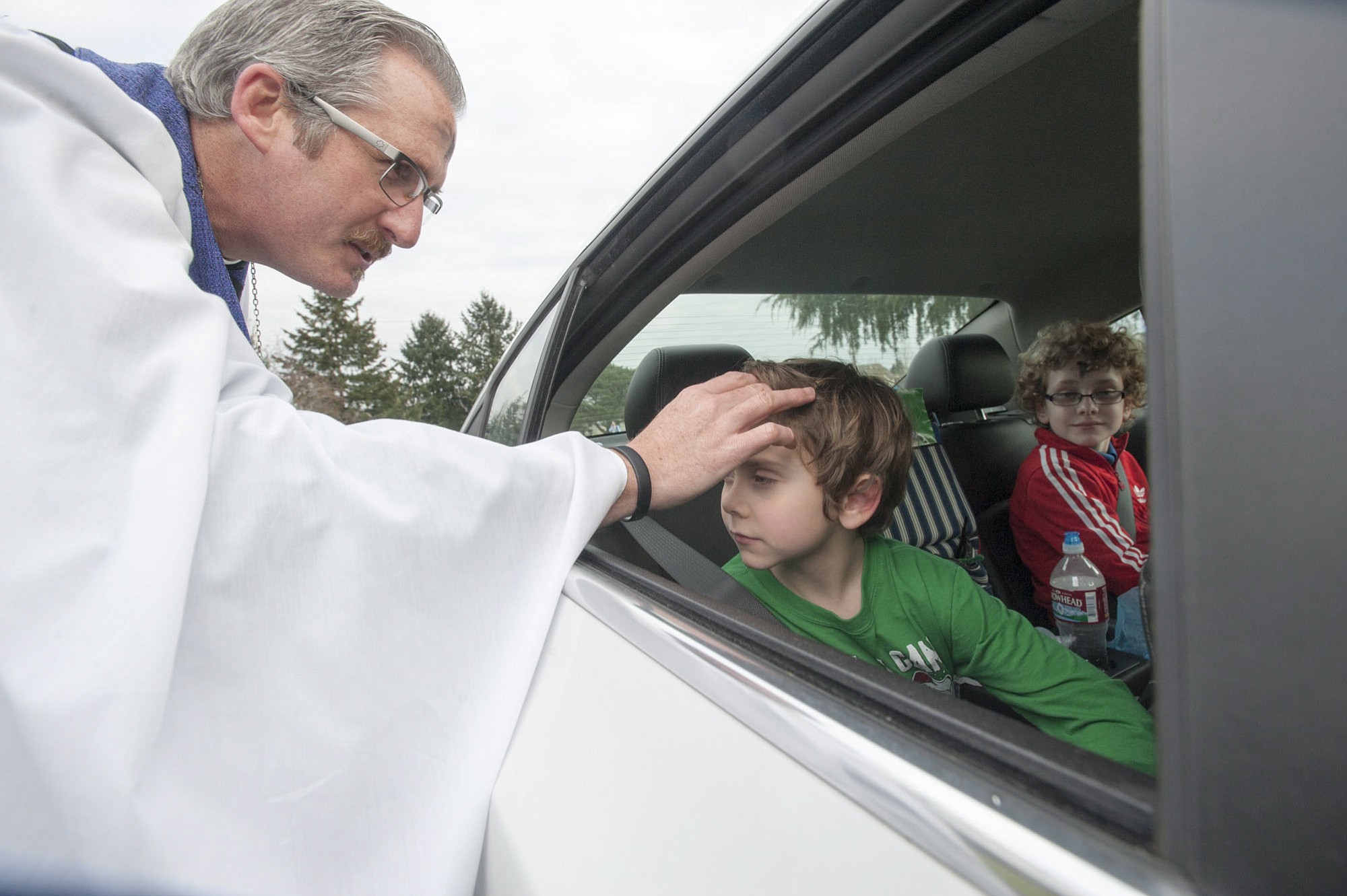 Gavin Waggoner, in green, gets smudged from the comfort of his car seat by the Rev. Tom Warne.