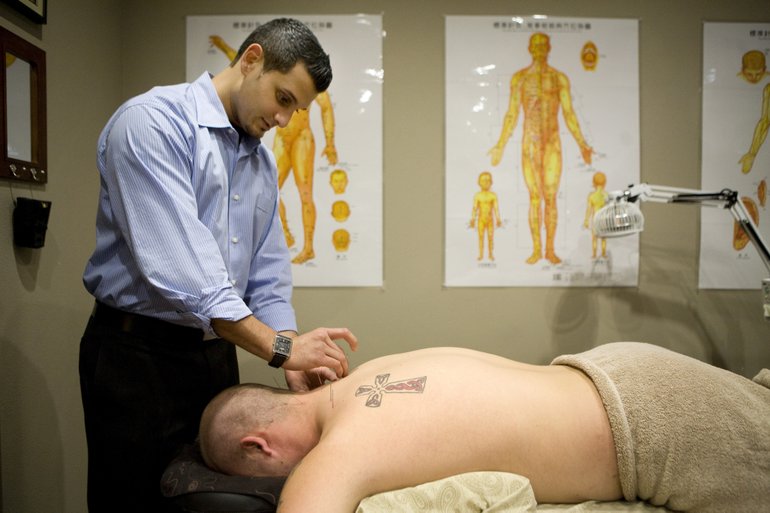 Vindi Khabra administers an acupuncture treatment to patient Nick Hazard to address Hazard's back pain.