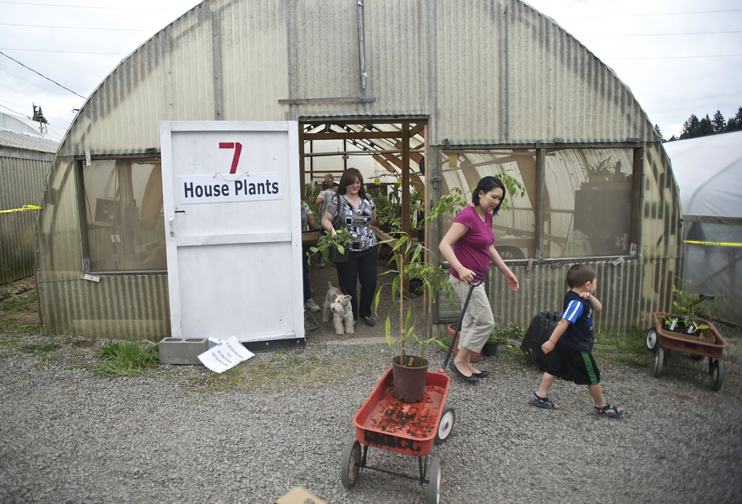 Nhu Rakoz, with her son, Edward, 4, pulls a wagon at the Mother's Day plant sale at the Heritage Farm on Sunday.