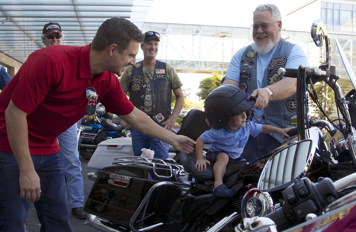 Westen Lodahl, 2, sits on a motorcycle as his dad, John Lodahl, left, and Brett Hockley help him.