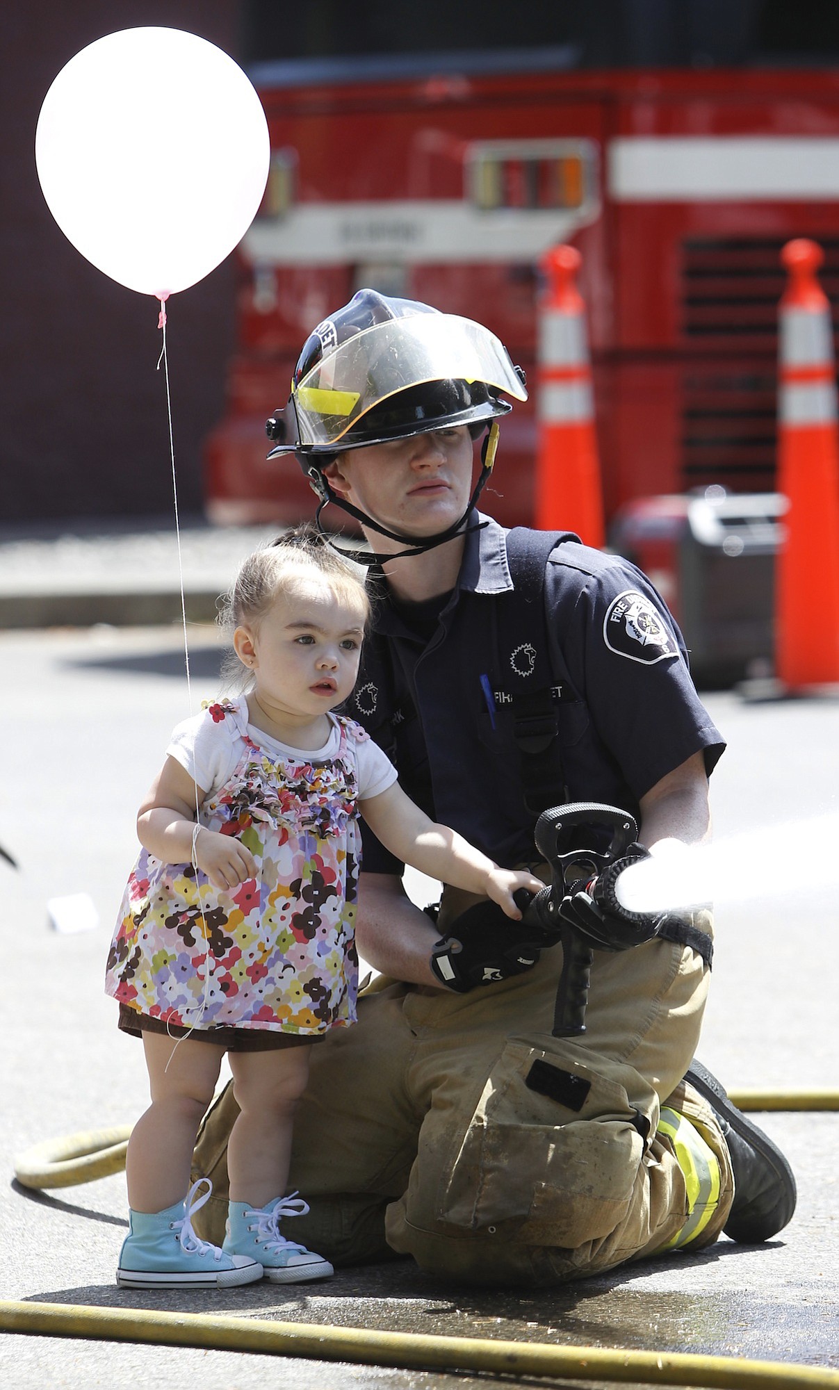 Two year old Alexis Legg lends some fire-hose assistance to Connor York, a Clark County fire cadet, during the Fire District 6.