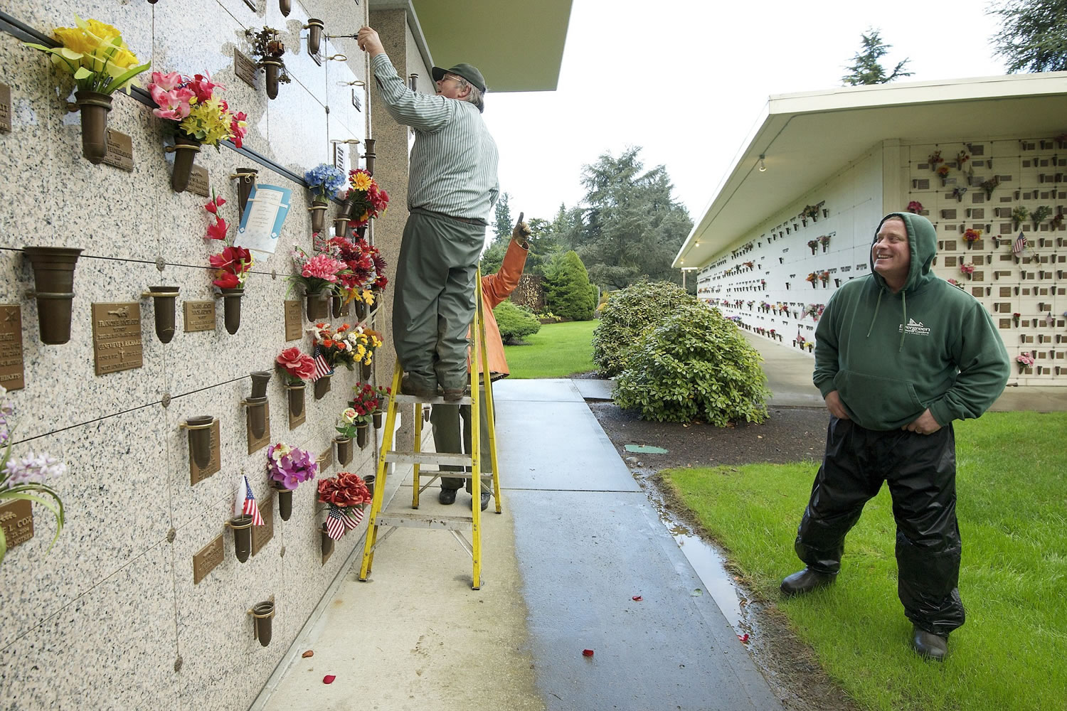 Greg Melum, grounds foreman for Evergreen Memorial Gardens cemetery, right, jokes with co-workers Joe A. Chipman, left, and Ruben Alonso, background, as Chipman prepares to place an urn into a niche of the mausoleum.