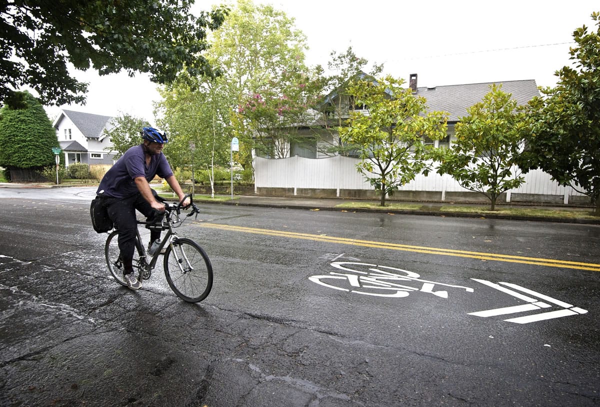 A bicyclist rides northbound past a sharrow marking on Columbia Street near West 23rd Street.