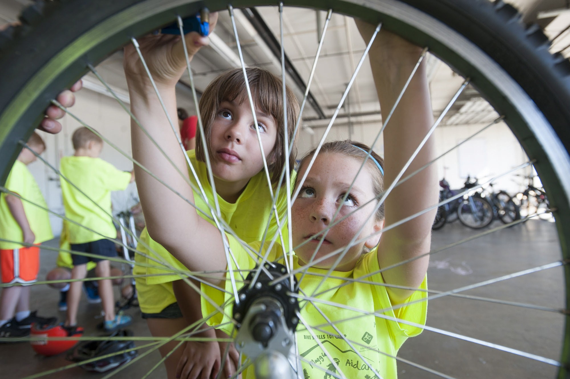 Adrianna Hatfield, right, works to separate a tire from a rim while Joycelyn Babcock watches during Bike 101, a weeklong day camp offered by the city of Vancouver.