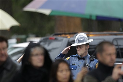 A Washington State Patrol trooper salutes in the rain as a procession of law enforcement vehicles pass by bearing the body of slain WSP trooper Tony Radulescu at the Mountain View Funeral Home on Feb. 24 in Lakewood, Wash. Radulescu was killed Thursday during a traffic stop in Gorst. A service for Radulescu begins at 1 p.m.