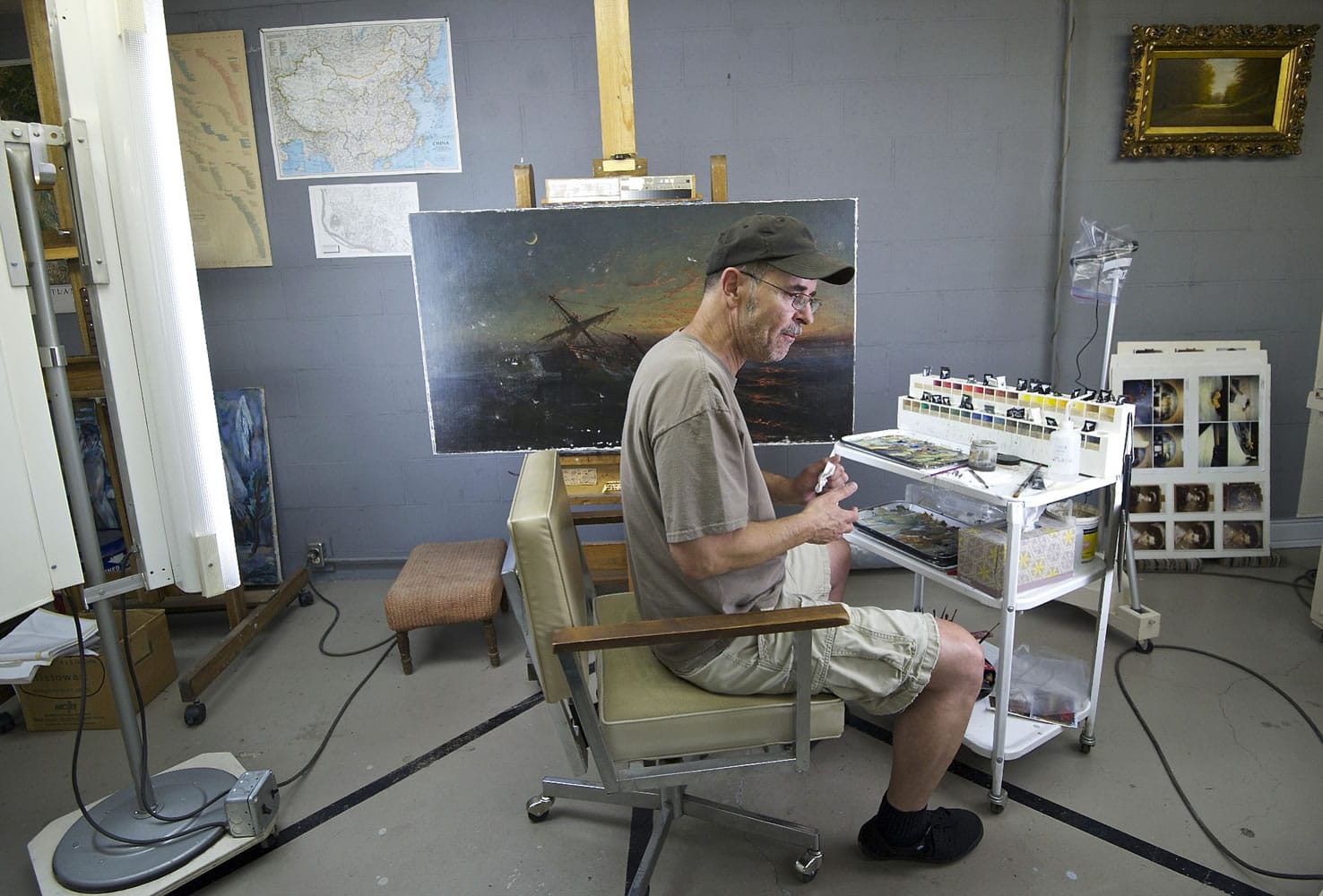 Troy Lucas, a fine arts conservator, works on a painting by an unidentified artist inside his lab.