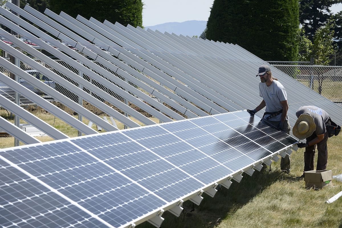 Bill Doile, left, and Will MacArthur install a solar panel for A