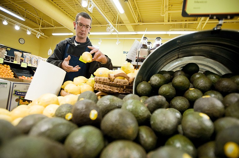 Ezra Irving stocks the produce section of the North Interstate New Seasons store in Portland in May.