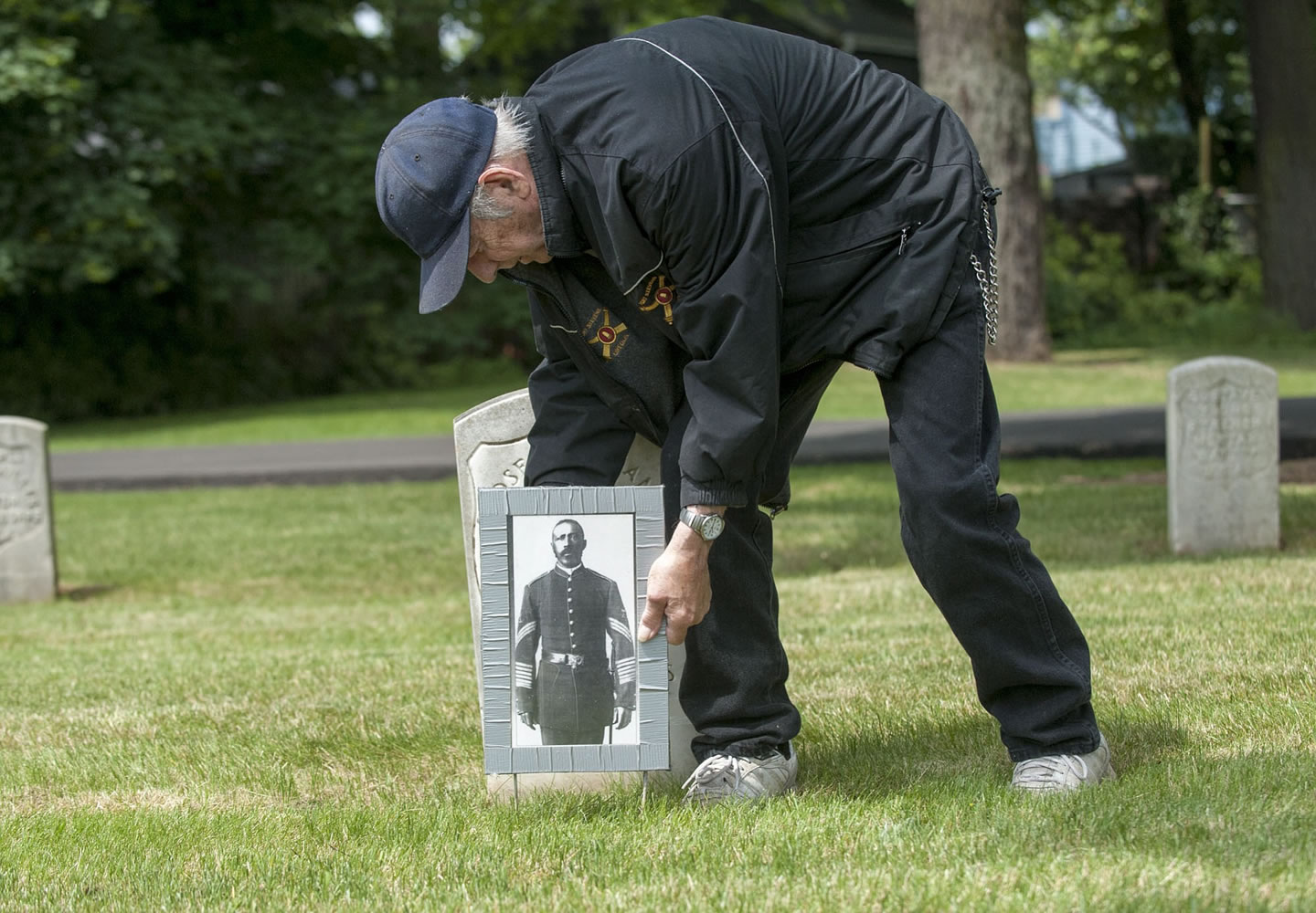 Military historian and volunteer Jack Buckmeir of Vancouver places a photograph of Moses Williams at his grave in the Vancouver Barracks Post Cemetery on Thursday, in honor of Memorial Day.