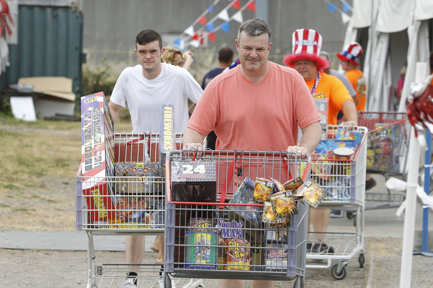 Eddie McGrath, from left, his father, Ed McGrath, and TNT Fireworks Warehouse's general manager, Beau Leach, push the McGraths' fireworks haul to their vehicle Sunday.