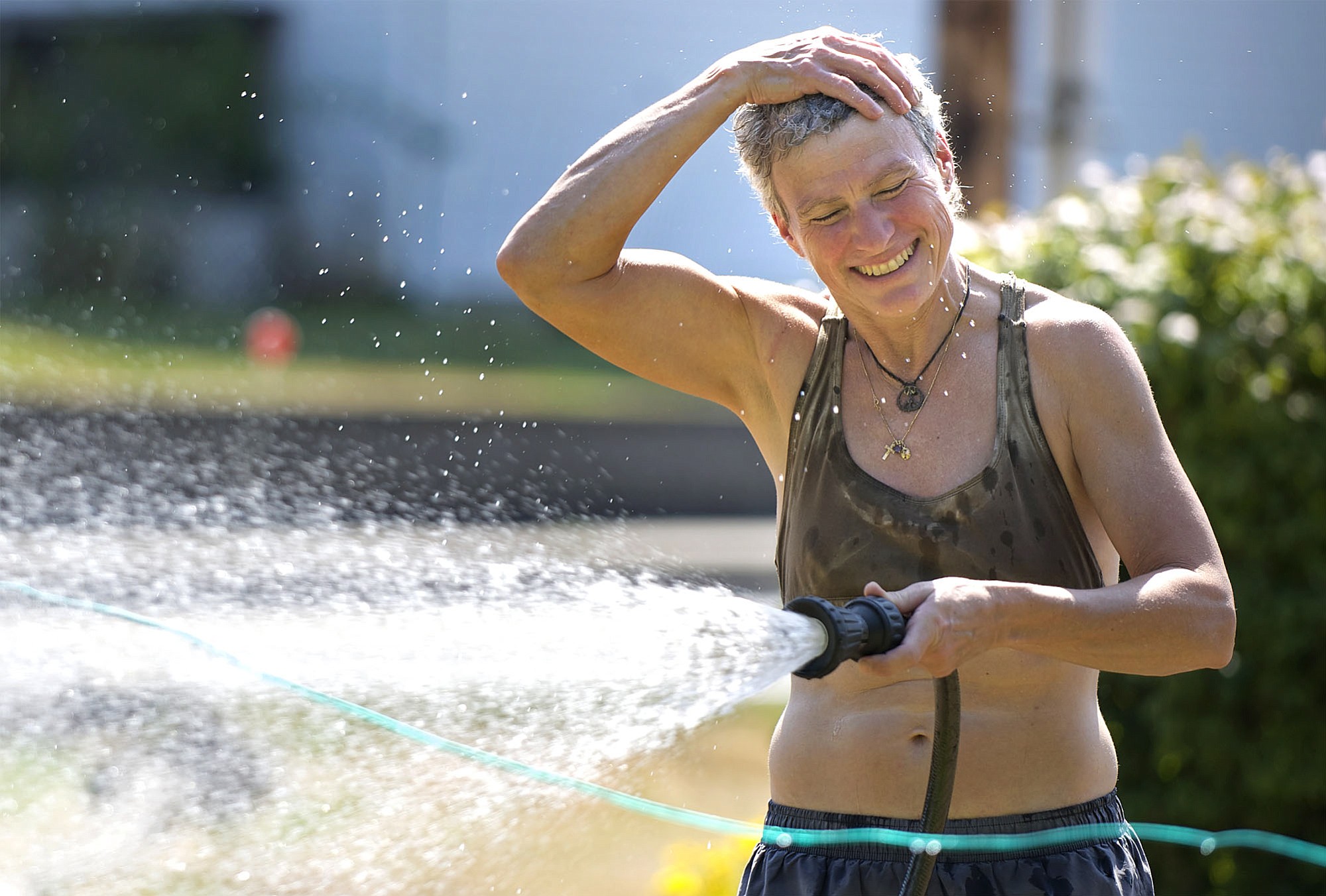 JR Ralston rubs water on her head as she waters her garden at her Felida home on Monday August 11, 2014.