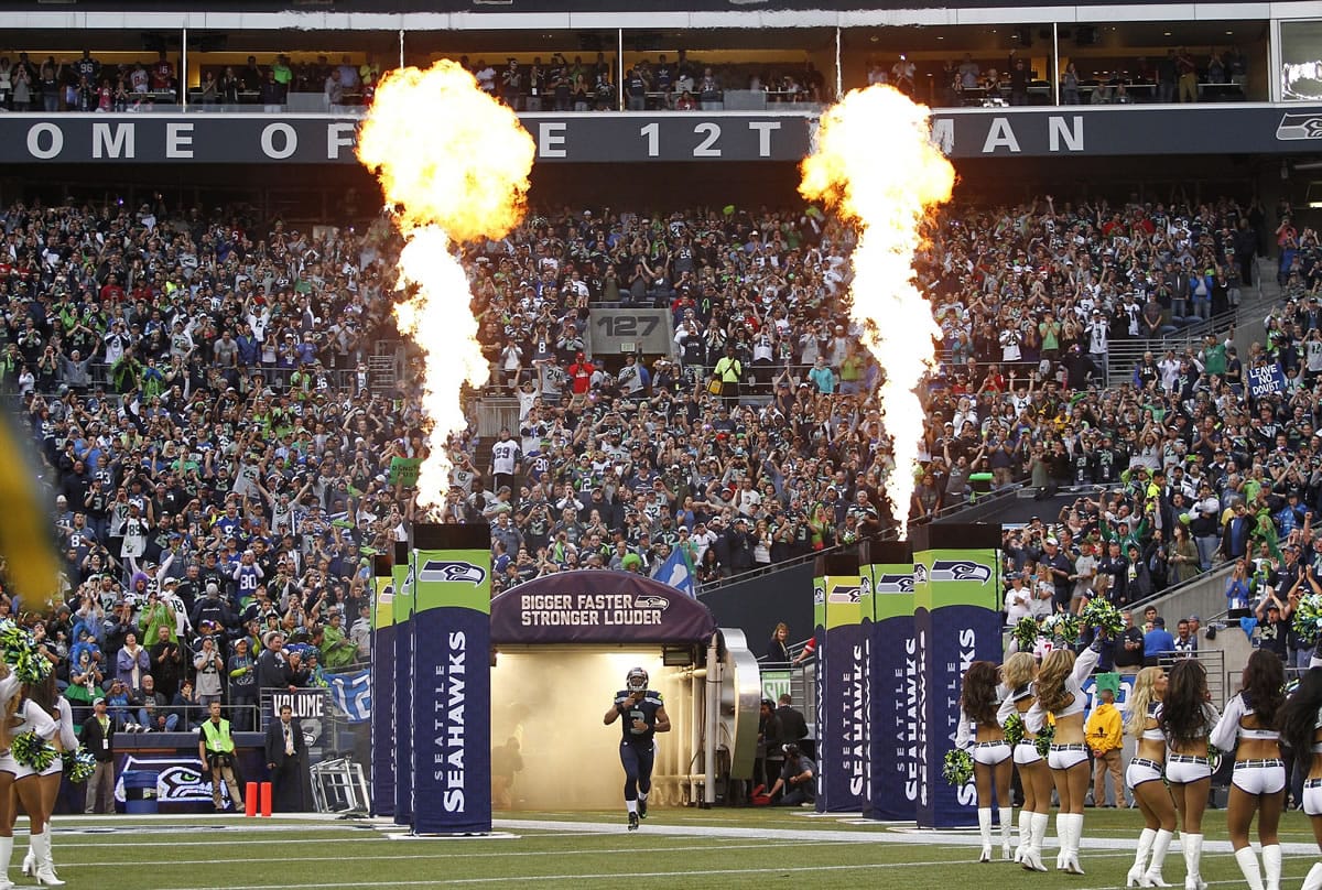 Seattle Seahawks quarterback Russell Wilson runs out of the tunnel as fire effects go off to take the field for the Seahawks' home opener NFL football game against the San Francisco 49ers, Sunday, Sept. 15, 2013, in Seattle.