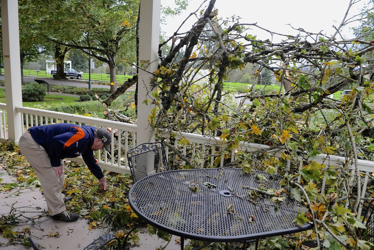 Grant House Restaurant owner Jon Taylor throws debris from the porch after a 150-year-old maple tree cracked and fell toward the historic building due to high winds Saturday.