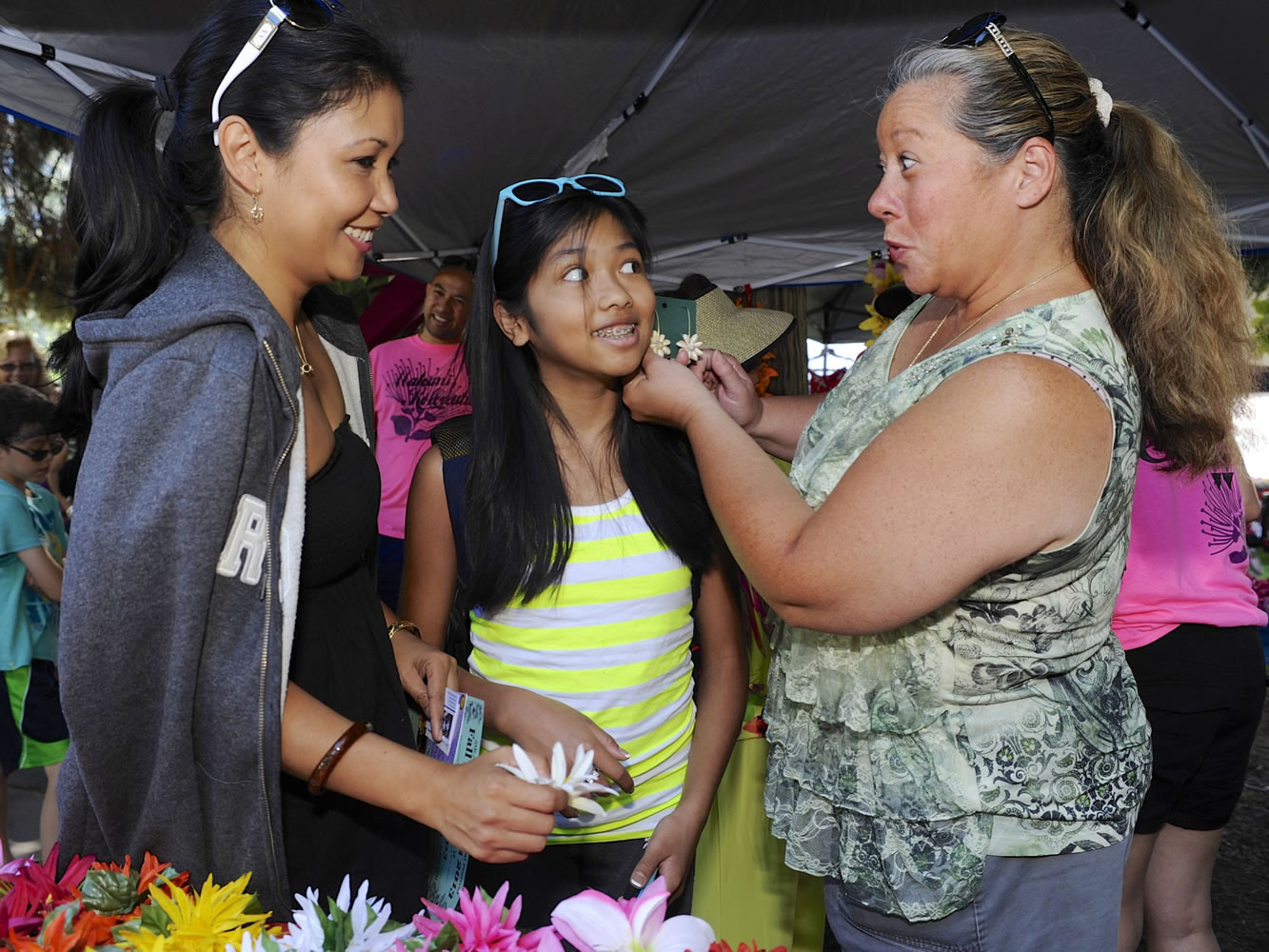 Kalei Sukhabut, left, choses a pua for her daughter, Sydney, with the help of Kuulei Gumapac, center, at the Ho'ike and Hawaiian Festival on Saturday at Esther Short Park in Vancouver.