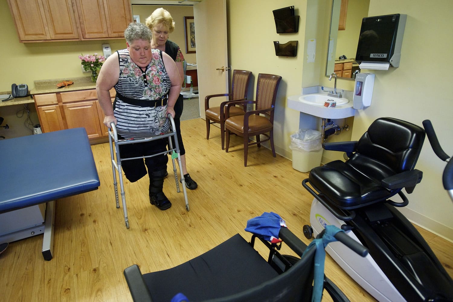 Physical therapist assistant Kathy Wiederman helps Kathy Hammersley walk using a walker at the Cascade Park Care Center.